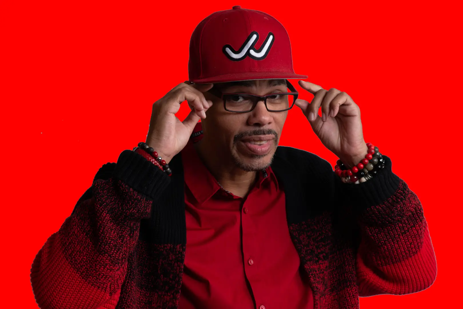 Untitled-8 (1) Man in red sweater, adjusting glasses.