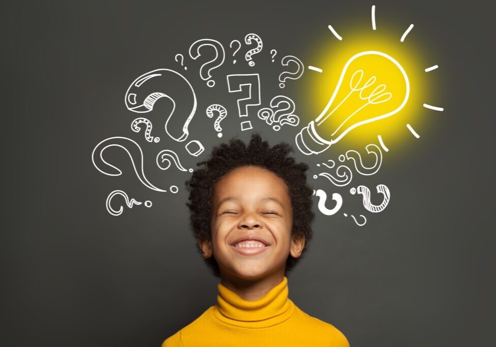 Happy black kid on black background with light bulb and question marks. Brainstorming and idea concept